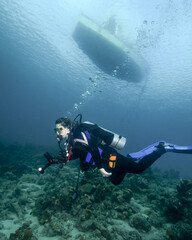 A Young Female Diver Swims Under a Dive Boat in Curacao