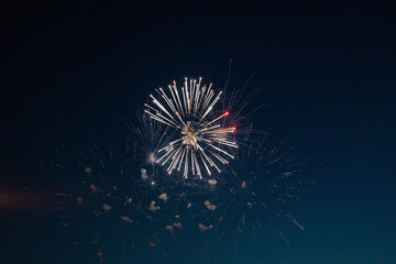 Firework over the blue sky at night, white, orange, red. Noise. Grain.