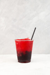 Fruit berries shaved ice in plastic cup. Slushie - drink on grey background. Refreshing summer drink with tapioca pearls. Take away food