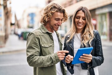 Man and woman couple smiling confident using touchpad at street