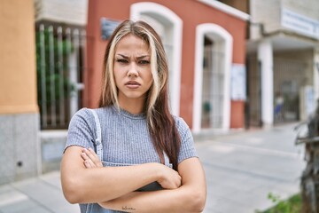 Young caucasian woman outdoors skeptic and nervous, disapproving expression on face with crossed arms. negative person.