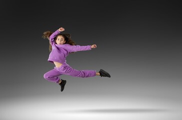 Concentrated athletic girl jumping during running. Modern healthy and sports youngster lifestyle.