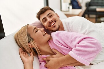 Young caucasian couple smiling happy and hugging lying on the bed at home.