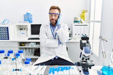 Fototapeta premium Middle age man working at scientist laboratory thinking looking tired and bored with depression problems with crossed arms.
