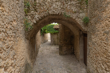 Fototapeta na wymiar Steinmauern mit einem Rundbogen in einem Dorf
