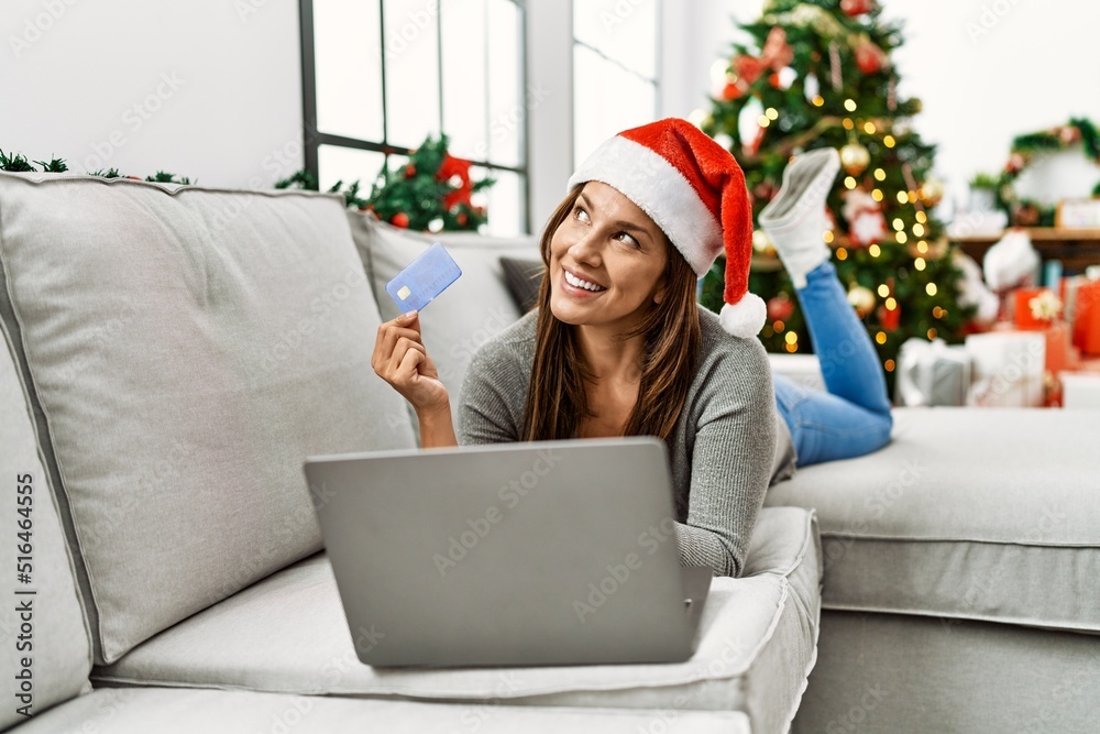 Sticker young latin woman using laptop and credit card lying by christmas tree at home