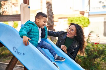 Mother and son playing on slide at park