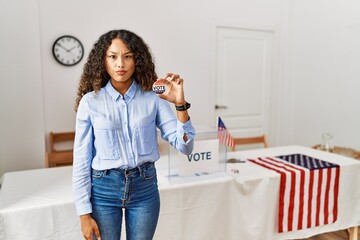 Beautiful hispanic woman standing by at political campaign by voting ballot skeptic and nervous, frowning upset because of problem. negative person.