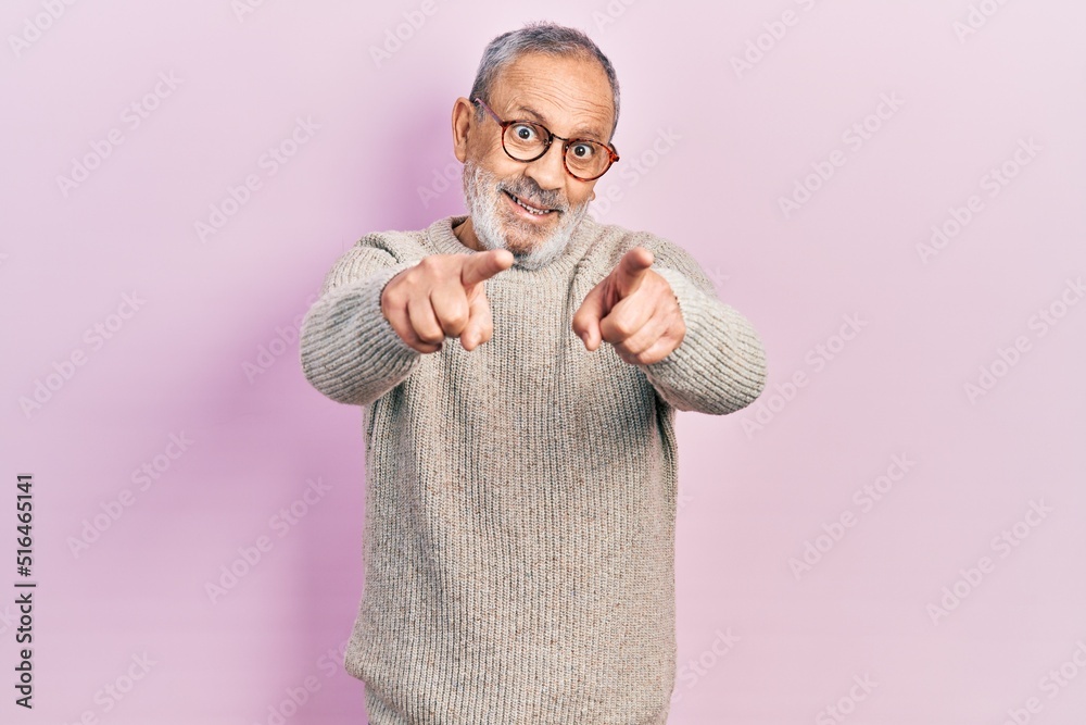 Wall mural handsome senior man with beard wearing casual sweater and glasses pointing to you and the camera wit