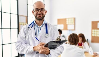 Group of young doctor working at the clinic office. Man smiling happy writing on clipboard.