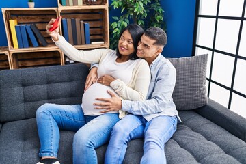 Young latin couple expecting baby make selfie by the smartphone at home