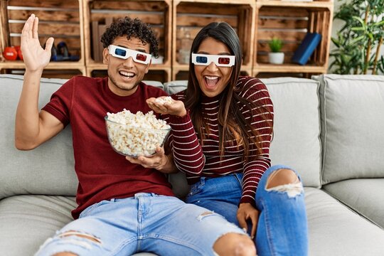 Young latin couple smiling happy sitting on the sofa at home.