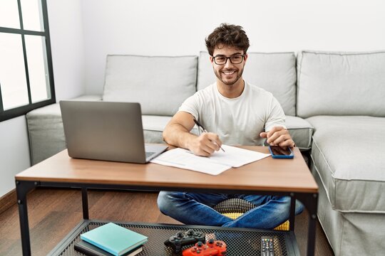 Hispanic man doing papers at home with a happy and cool smile on face. lucky person.