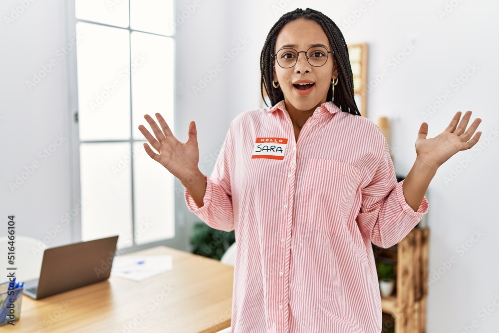 Poster Young african american woman wearing hello my name is sticker identification celebrating victory with happy smile and winner expression with raised hands