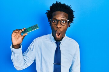 Young african american man holding computer ram scared and amazed with open mouth for surprise,...
