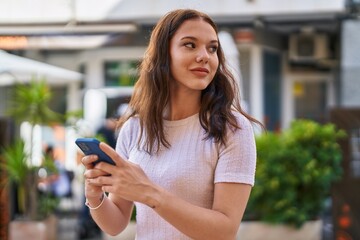 Young woman smiling confident using smartphone at street