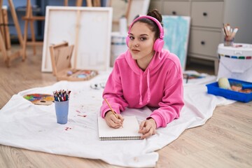 Young woman artist listening to music drawing on notebook at art studio