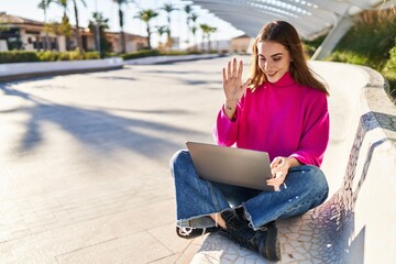 Young woman having video call sitting on bench at park