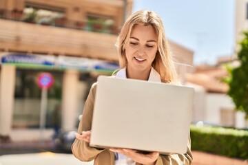 Young blonde woman executive smiling confident using laptop at street