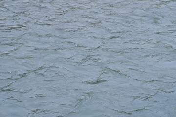 The blurred surface of the river water with large ripples and waves.