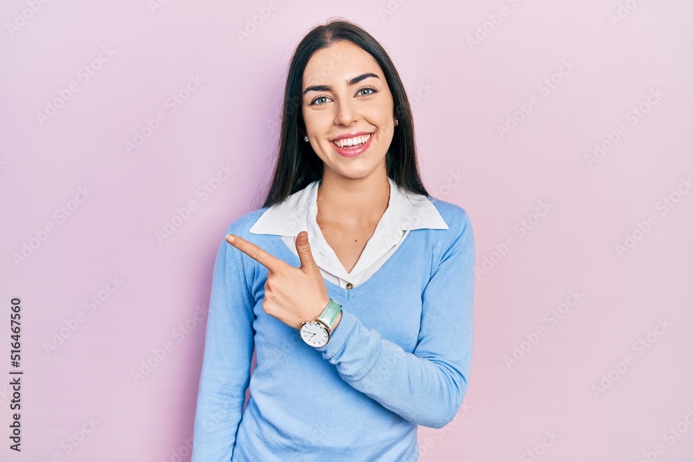 Poster Beautiful woman with blue eyes standing over pink background cheerful with a smile of face pointing with hand and finger up to the side with happy and natural expression on face