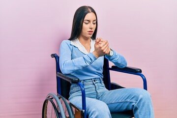 Beautiful woman with blue eyes sitting on wheelchair suffering pain on hands and fingers, arthritis...