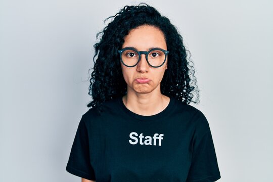 Young hispanic woman with curly hair wearing staff t shirt depressed and worry for distress, crying angry and afraid. sad expression.
