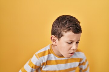 Young caucasian kid standing over yellow background with hand on stomach because indigestion, painful illness feeling unwell. ache concept.