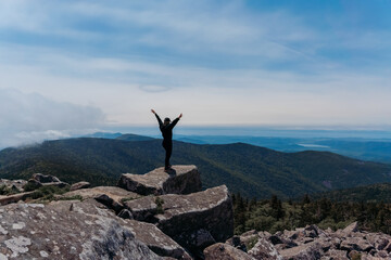 A girl on top of Mount Pidan looks at a beautiful mountain valley in the fog in summer. Travel and tourism. Hiking