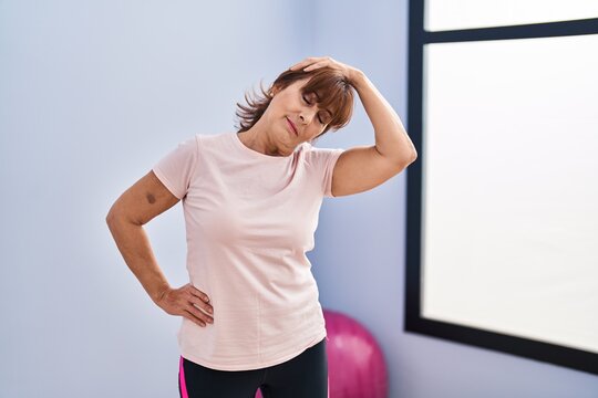 Middle age woman stretching head at sport center