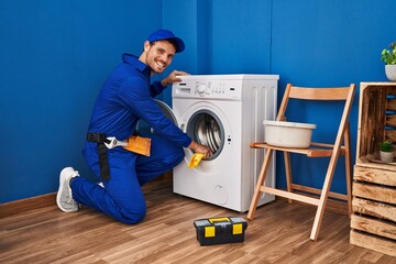 Young hispanic man technician cleaning washing machine at laundry room