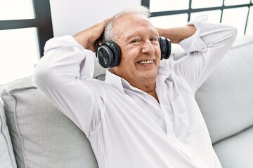 Senior man listening to music sitting on sofa at home