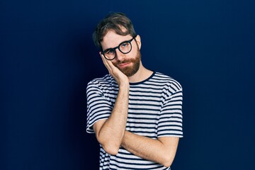 Fototapeta na wymiar Caucasian man with beard wearing striped t shirt and glasses thinking looking tired and bored with depression problems with crossed arms.