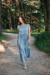Lovely girl in summer dress walking forest road