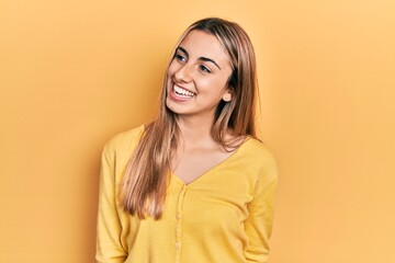 Obraz premium Beautiful hispanic woman wearing casual yellow sweater looking away to side with smile on face, natural expression. laughing confident.