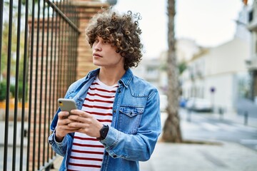 Fototapeta premium Young hispanic man using smartphone at the city
