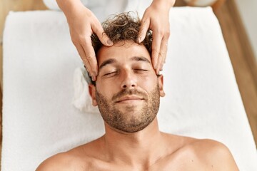 Fototapeta na wymiar Young hispanic man having facial massage at beauty center