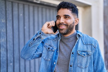 Young hispanic man smiling confident talking on the smartphone at street