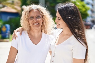 Two women mother and daughter hugging each other at street