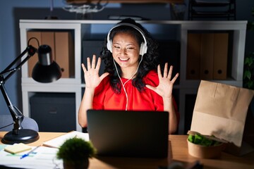 Young asian woman working at the office with laptop at night showing and pointing up with fingers...