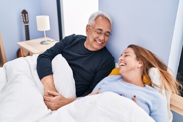 Middle age man and woman couple smiling confident lying on bed at bedroom