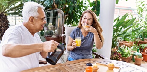 Middle age hispanic couple smiling happy having breakfast at the terrace.