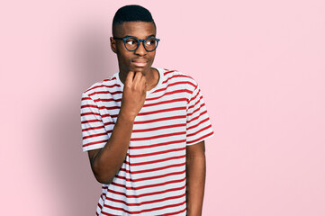 Young african american man wearing casual t shirt and glasses looking stressed and nervous with hands on mouth biting nails. anxiety problem.