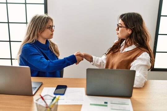 Two business workers woman shaking hands at the office.