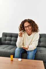 Middle age hispanic woman smiling confident taking pills at home