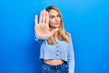 Young caucasian woman wearing casual clothes doing stop sing with palm of the hand. warning expression with negative and serious gesture on the face.