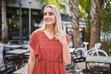 Young blonde girl smiling happy standing at the city.