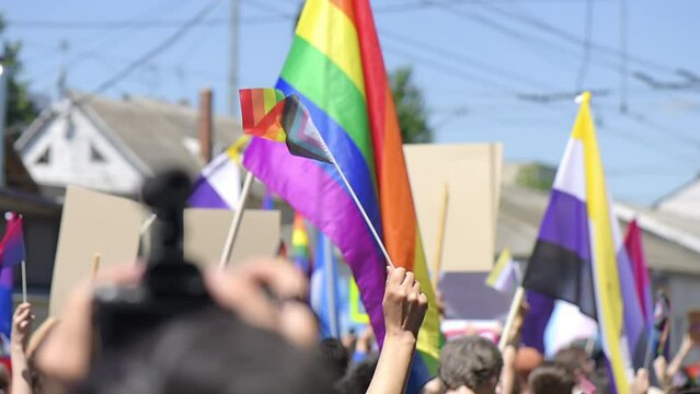 Lots of people at the gay pride parade in the center of Chisinau, Moldova. Multiple rainbow flags and posters. Slow motion