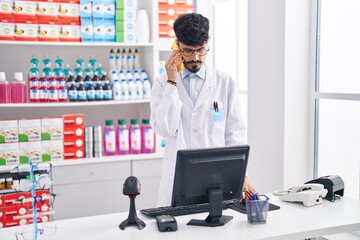 Fototapeta na wymiar Young hispanic man pharmacist talking on smartphone working at pharmacy