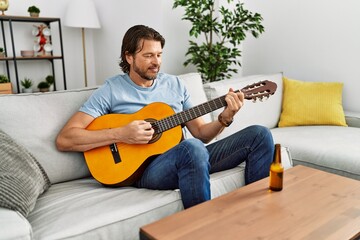 Middle age caucasian man smiling confident playing classical guitar at home